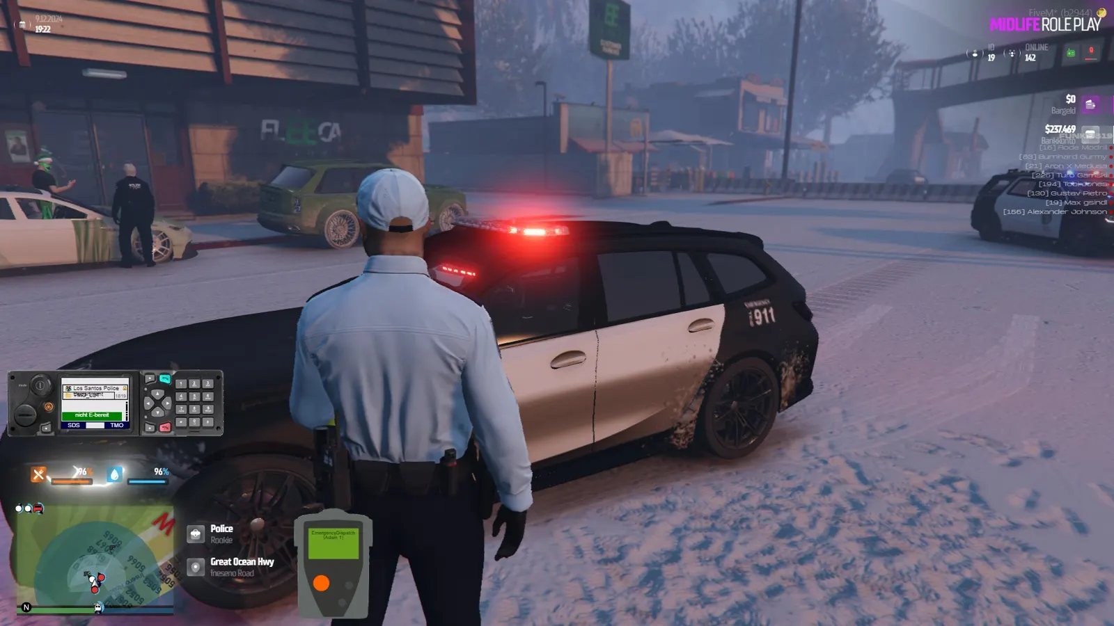 Polizist im Schnee neben einem Streifenwagen